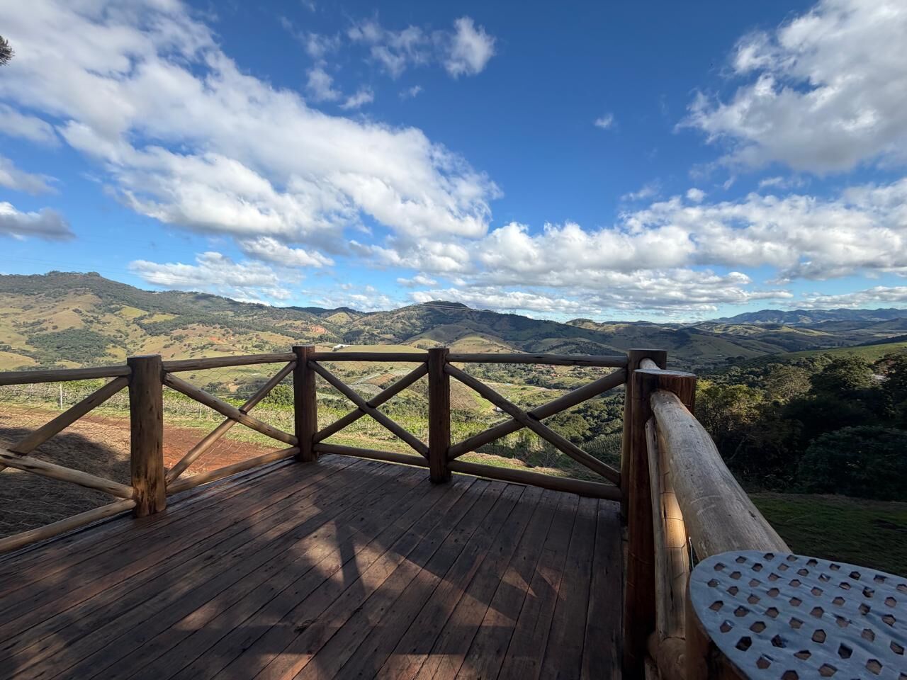Eine Holzterrasse mit Geländer, mit Blick auf eine gebirgige Landschaft.