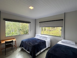 A bedroom with two beds, a desk, and large windows. - Deusmideu Refuge (São Bento do Sapucaí)
