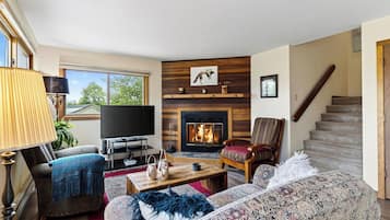 A living room with a fireplace, a television, a sofa, and a chair.