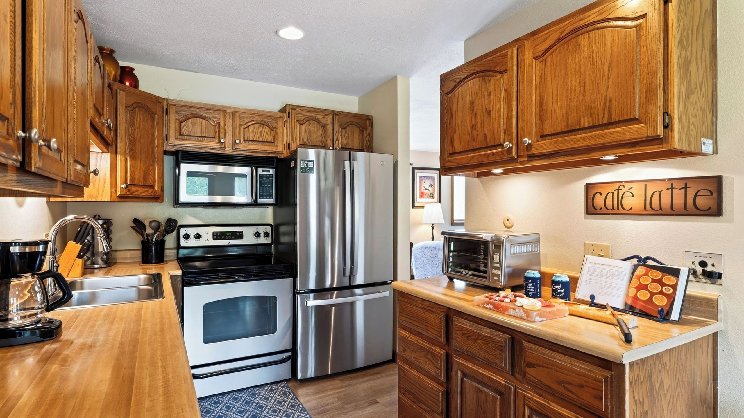 A modern kitchen with stainless steel appliances, wooden cabinets, and a countertop with food items.