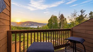 Eine Holzterrasse mit Blick auf einen Sonnenuntergang über Bergen und einem See.