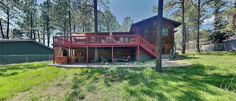 A wooden cabin with a covered porch and a staircase leading to a deck.