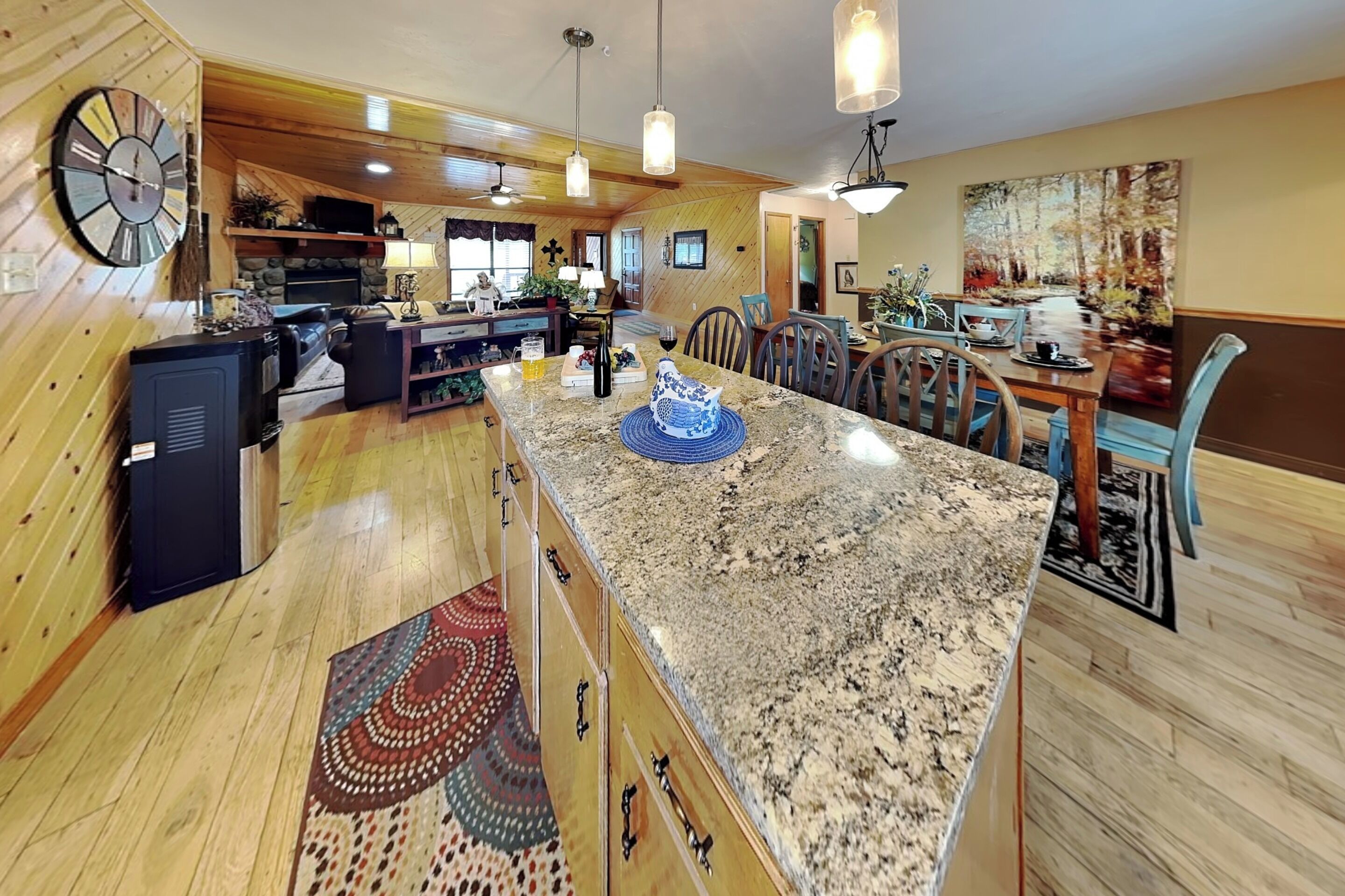 A spacious kitchen with granite countertops, wooden cabinets, and a dining area with a table and chairs.