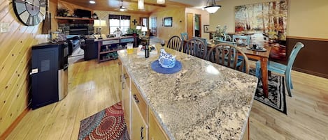 Una cocina amplia con encimeras de granito, armarios de madera y un comedor con mesa y sillas.