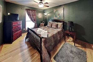 A bedroom with a bed, dresser, nightstand, lamp, and a ceiling fan. - Casa Aurora (Ruidoso)