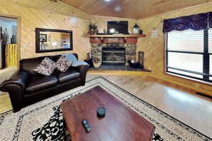 Ein gemütliches Wohnzimmer mit Kamin, einer Ledersofa, einem Couchtisch und einem großen Fenster mit Jalousien.