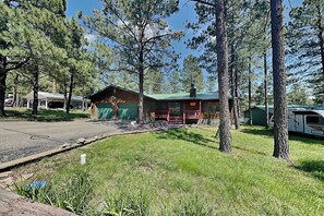 A cabin with a green roof, a covered porch, and a garage. - Casa Aurora (Ruidoso)
