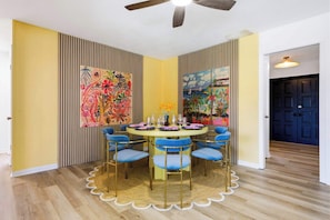 A dining area with a round table, blue chairs, and artwork on the walls. - Pool •  Hot Tub•  Putt Putt • Game Room •  Karaoke (Largo)