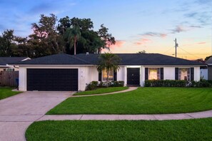 A single-story house with a dark roof, a garage, and a well-maintained lawn. - Pool •  Hot Tub•  Putt Putt • Game Room •  Karaoke (Largo)