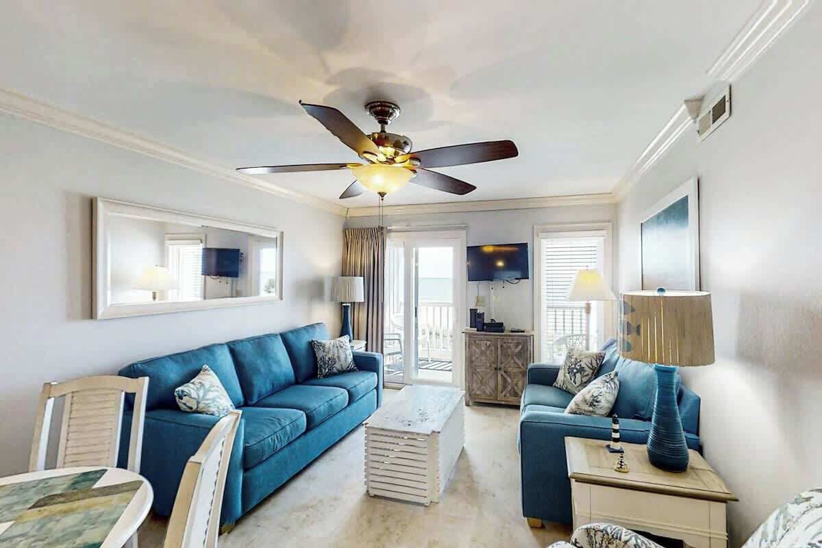 A living room with a ceiling fan, two sofas, a coffee table, and a TV.