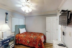 A bedroom with a bed, a desk, a chair, a ceiling fan, a window with blinds, and a door. - A Place at the Beach V - A307 (Myrtle Beach)