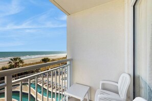 A balcony with a view of a beach and a pool area. - Bay Watch Resort 0335 (North Myrtle Beach)