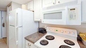 Cozinha com eletrodomésticos brancos, incluindo geladeira, micro-ondas e fogão.