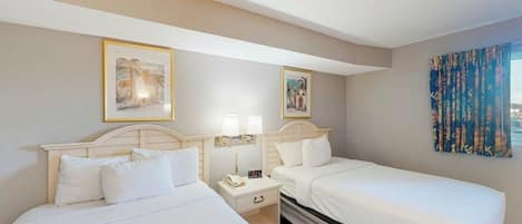 A hotel room with two beds, a nightstand with a lamp, and a window with curtains.