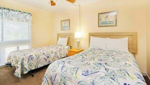 A hotel room with two beds, a ceiling fan, a window with blinds, and wall art. - Arcadian Dunes 02-207 (Myrtle Beach)