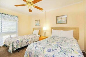 A hotel room with two beds, a ceiling fan, a window with blinds, and wall art. - Arcadian Dunes 02-207 (Myrtle Beach)