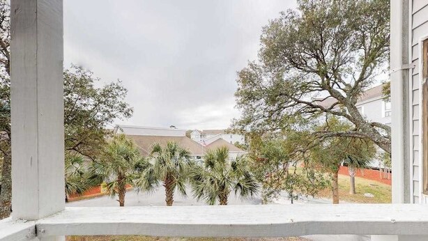 A view from a balcony with a railing, overlooking a courtyard with palm trees and a building in the background. - Arcadian Dunes 02-208 (Myrtle Beach)