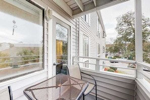A balcony with a metal table and chairs, overlooking a residential street. - Arcadian Dunes 02-208 (Myrtle Beach)