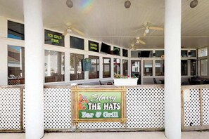 Un espace extérieur aménagé avec des sièges et une enseigne indiquant « Harry The Hats Bar & Grill ».