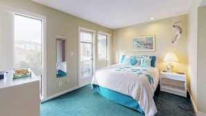 A bedroom with a bed, bedside table, lamp, and a window with a view. - Arcadian Dunes 02-208 (Myrtle Beach)
