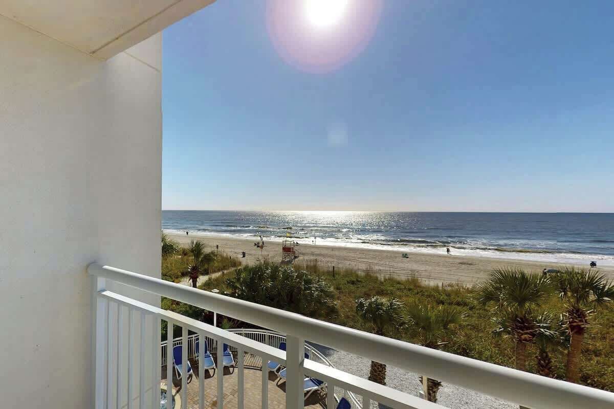 A balcony with a view of a beach and ocean.