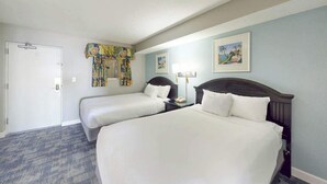 Ein Hotelzimmer mit zwei Betten, einer Tür, einem Fenster mit Vorhängen und einer Wand mit zwei gerahmten Bildern.