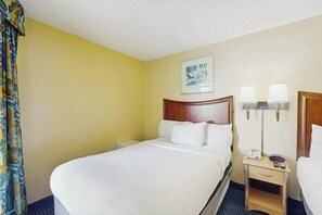 A hotel room with a large bed, a bedside table with lamps, and a painting on the wall. - Bay Watch Resort 0310 (North Myrtle Beach)