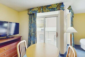A hotel room with a television, a dining table, two chairs, a balcony with a view, and a bed. - Bay Watch Resort 0310 (North Myrtle Beach)