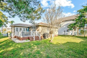 A residential house with a front porch, a small deck, and a well-maintained lawn. - Cozy Beach House 314 (North Myrtle Beach)