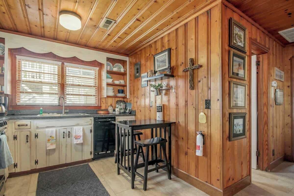 Eine Küche mit Holzausbau, einem Spülbecken und einer Bar mit Hockern.