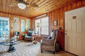 A wooden interior with wicker furniture, a glass table, and a door with a no-smoking sign. - Cozy Beach House 314 (North Myrtle Beach)