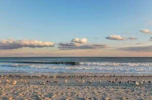 Ein Strand mit Wellen und einem Felsen im Hintergrund.
