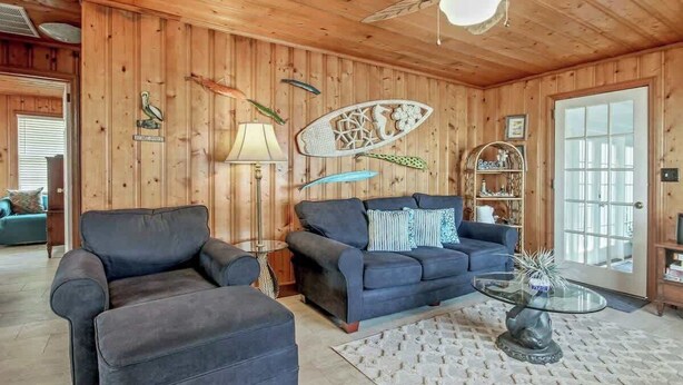 A cozy living room with a wooden ceiling, a ceiling fan, a sofa, a coffee table, and decorative items. - Cozy Beach House 314 (North Myrtle Beach)