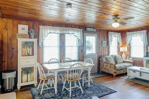 A wooden interior with a dining table, chairs, a sofa, and a ceiling fan. - Ocean Gem (North Myrtle Beach)