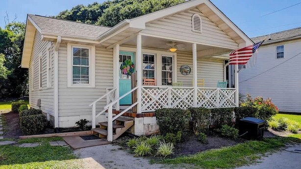 Ein eingeschossiges Haus mit Veranda, Eingangstür und kleinem Garten.