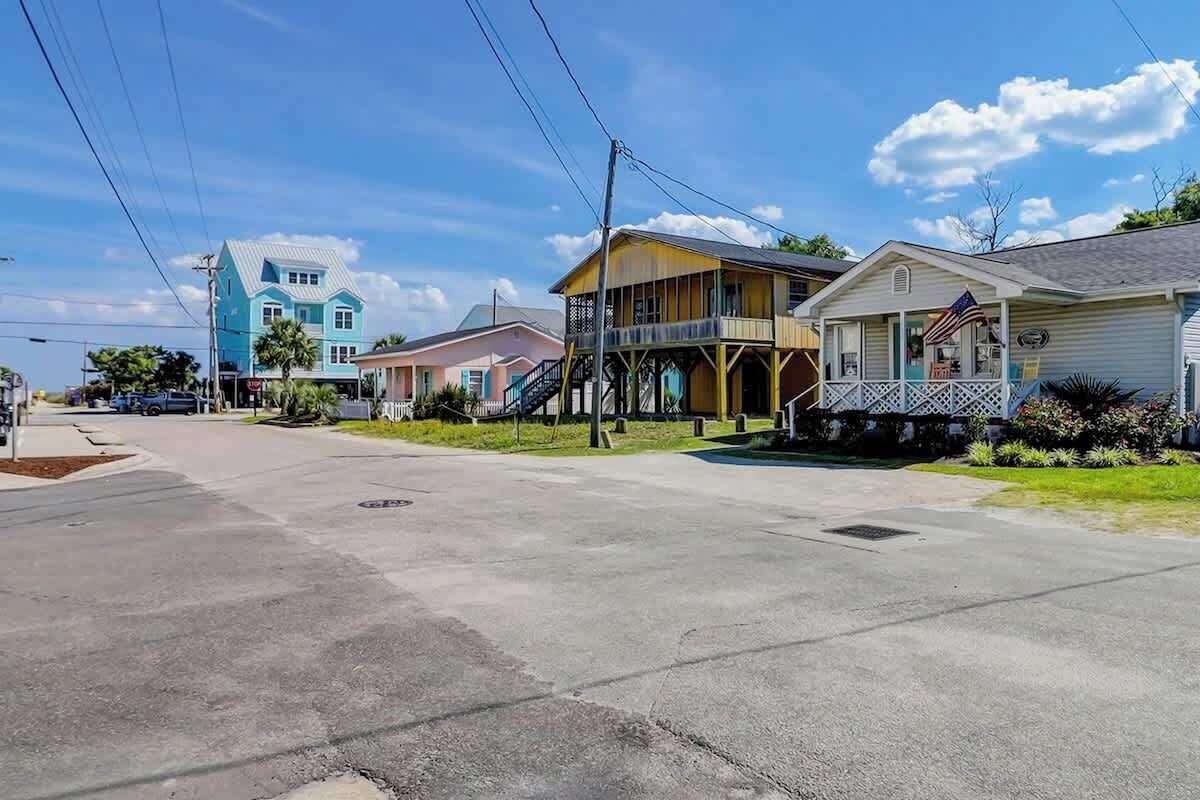 Une rue résidentielle bordée de maisons, avec un ciel dégagé et un trottoir.