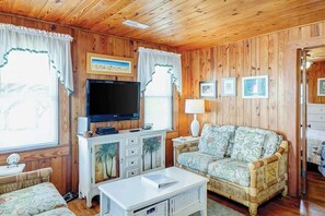 A wooden-paneled room with a television, sofa, and framed pictures on the wall. - Ocean Gem (North Myrtle Beach)