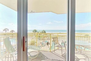 Ein Balkon mit Blick auf den Strand, einen Pool und Gartenmöbel.