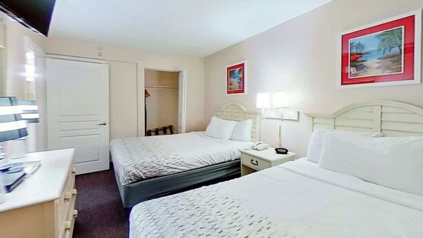 Ein Hotelzimmer mit zwei Betten, einem Schreibtisch, einem Fernseher und einem Kleiderschrank.