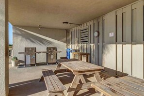 An outdoor patio area with a grill, a table, and benches. - Oceanfront Arcadian II  8D (Myrtle Beach)