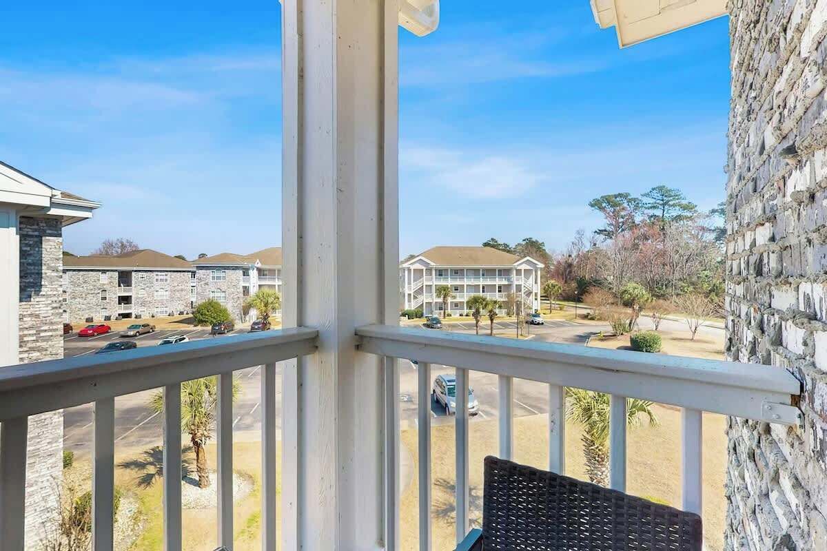A balcony with a view of a parking lot and buildings.