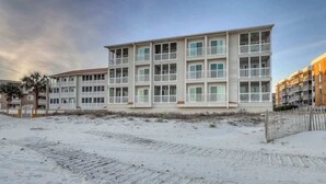 Ett hotell med flera våningar och balkonger, beläget nära en sandstrand.