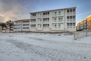 Ein mehrstöckiges Hotel mit Balkonen in der Nähe eines Sandstrandes.