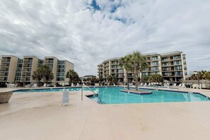 A hotel with a swimming pool, multiple balconies, and palm trees. - Palmetto Sunrise Waterfront Condo (Litchfield Beach)