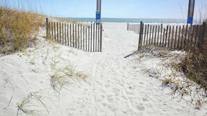 A sandy beach path leading to the ocean, flanked by wooden fences. - Arcadian Dunes 19-374 (Myrtle Beach)