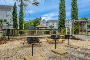 Eine Außenpatio-Terrasse mit Grillanlagen, Picknicktischen und einem Pavillon.