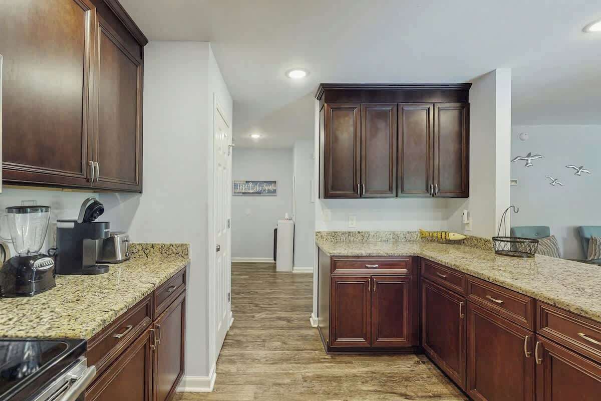 A kitchen with dark wood cabinets, granite countertops, and a central island.