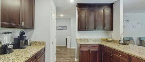 A kitchen with dark wood cabinets, granite countertops, and a central island.