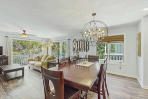 A spacious dining area with a large wooden table, multiple chairs, a chandelier, and a ceiling fan. - Dry Dock Condo Unit 204 (Myrtle Beach)