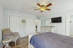 A bedroom with a bed, a chair, a dresser, a ceiling fan, and a television. - Dry Dock Condo Unit 204 (Myrtle Beach)